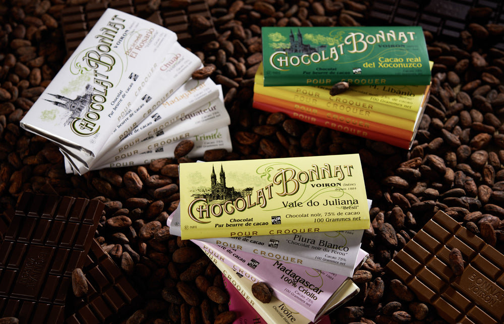 Tablettes de chocolat Bonnat Grands Crus Historiques et Grands Crus d'Exception sur un lit de fèves de cacao.