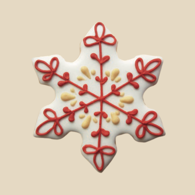 Biscuit en forme de flocon décoré de glaçage blanc, rouge et jaune en motifs symétriques.