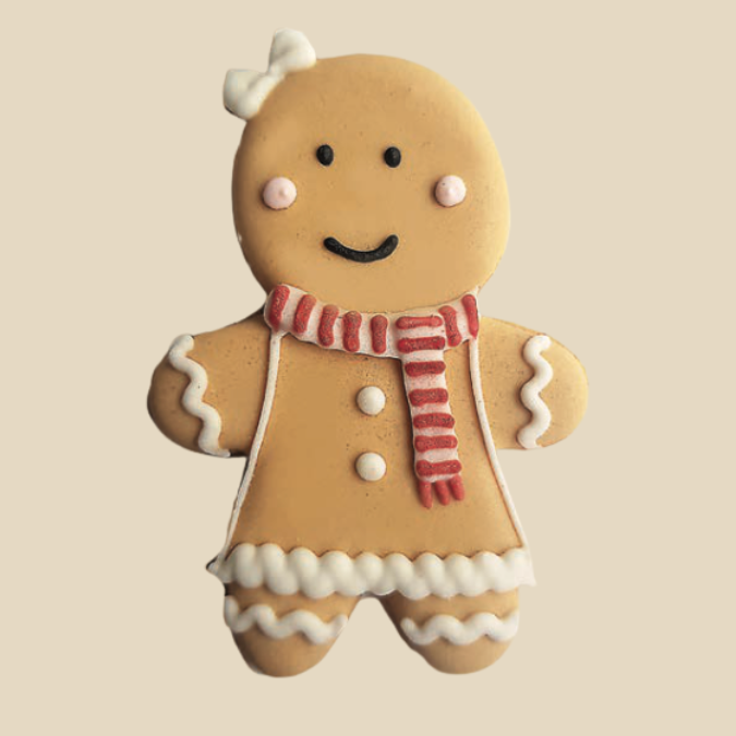 Biscuit pain d’épices en forme de fillette, décoré avec robe, écharpe rouge et nœud blanc.