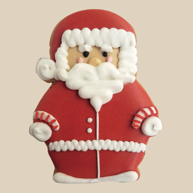 Biscuit Fabulous Biscuits décoré en forme de Père Noël, glaçage rouge et blanc sur fond uni beige.
