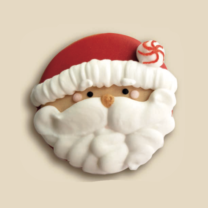 Biscuit rond décoré en visage de Père Noël, avec bonnet rouge et barbe blanche en glaçage.