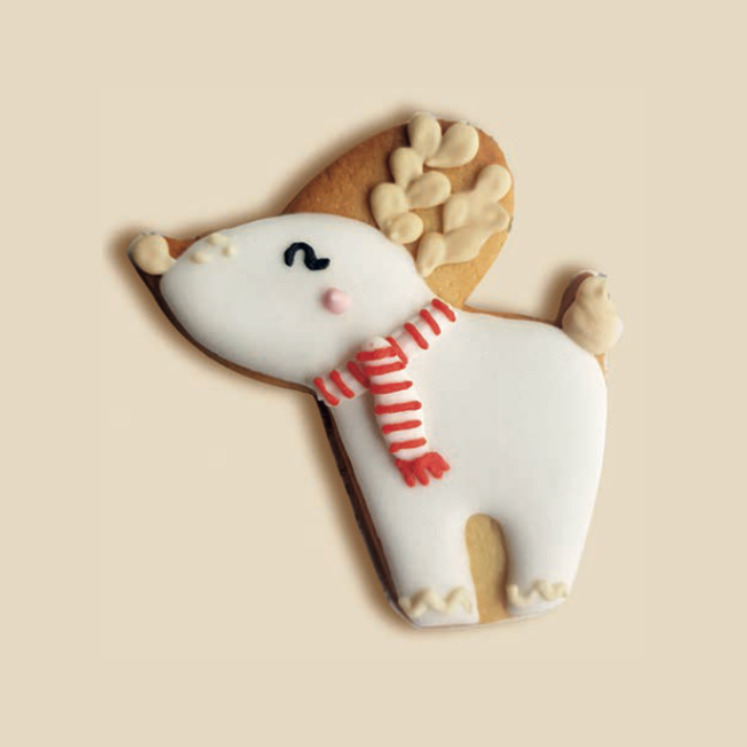 Biscuit en forme de renne blanc avec écharpe rouge, bois beiges et décor en glaçage.