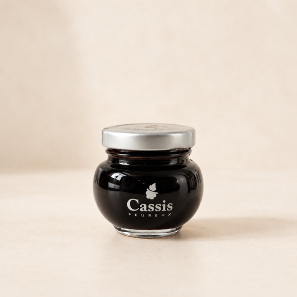 Cassis à la crème de cassis Peureux en petit pot en verre avec couvercle argenté, fond clair.