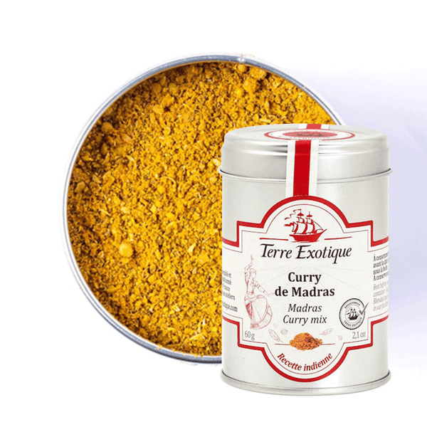 Boîte métallique de Curry de Madras - Terre Exotique, contenant un mélange d'épices vibrant inspiré de la recette traditionnelle indienne. Une poudre jaune intense, finement texturée, est présentée dans un récipient ouvert à l'arrière-plan