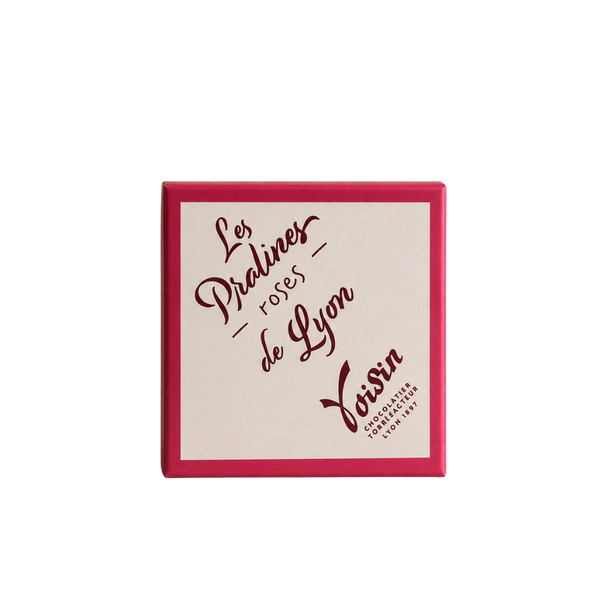 Boîte de Pralines roses de Lyon Voisin, confiserie lyonnaise, emballage rose et blanc sur fond uni.