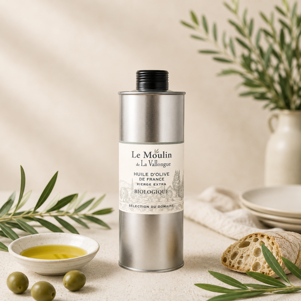 Huile d’olive vierge extra biologique de France en bidon métallique, présentée avec olives vertes, pain artisanal et branches d’olivier.