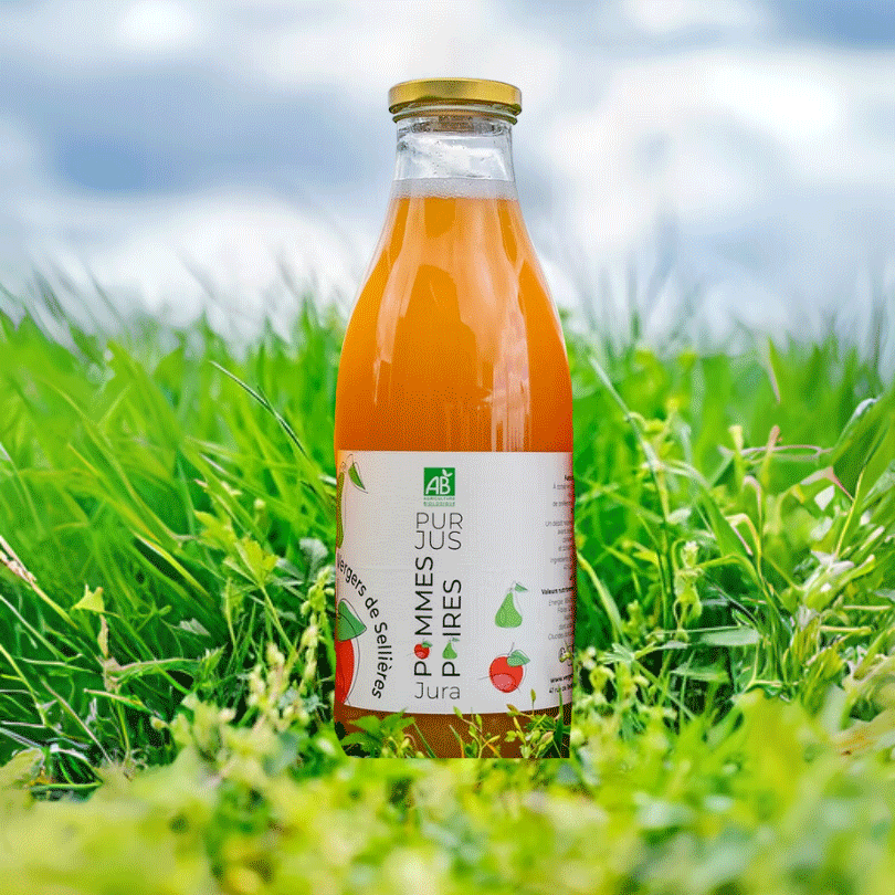 Bouteille d’un litre de pur jus pommes-poires bio posée dans de l'herbe. L’étiquette blanche met en avant le label AB (Agriculture Biologique), avec des illustrations de pommes et de poires, et la mention "Vergers de Sellières - Jura". 