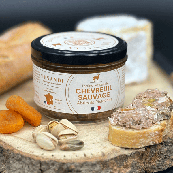 Terrine de chevreuil sauvage avec abricots secs, pistaches et toast sur planche rustique.