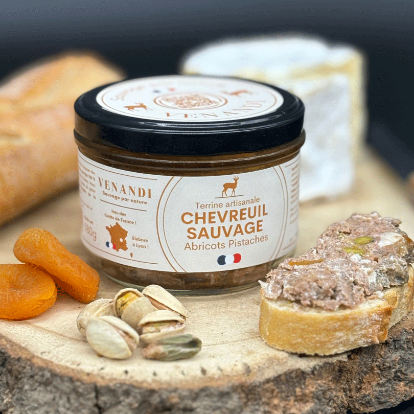 Terrine de chevreuil sauvage avec abricots secs, pistaches et toast sur planche rustique.