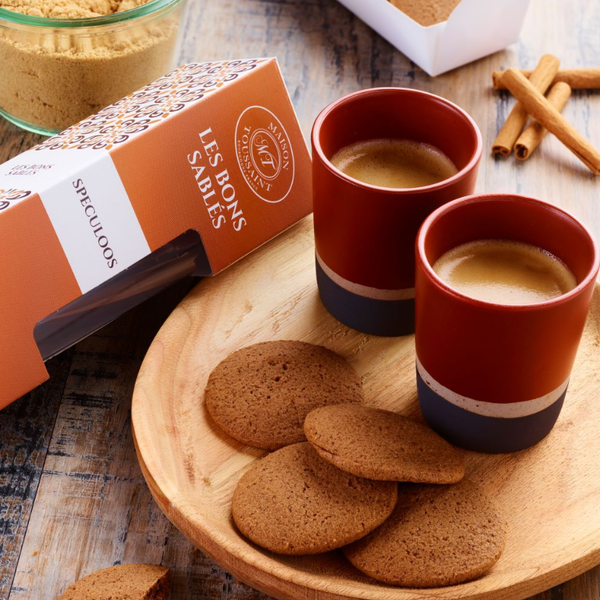 Biscuits spéculoos dorés Maison Toussaint servis avec deux cafés, sur une planche en bois rustique.