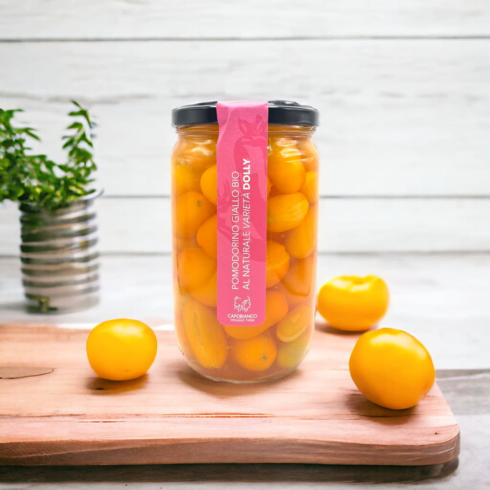 Tomates cerises jaunes variété Dolly biologiques cueillies à la main lorsqu'elles sont complètement mûres, lavées et emballées avec de l'eau et du sel dans des bocaux en verre.