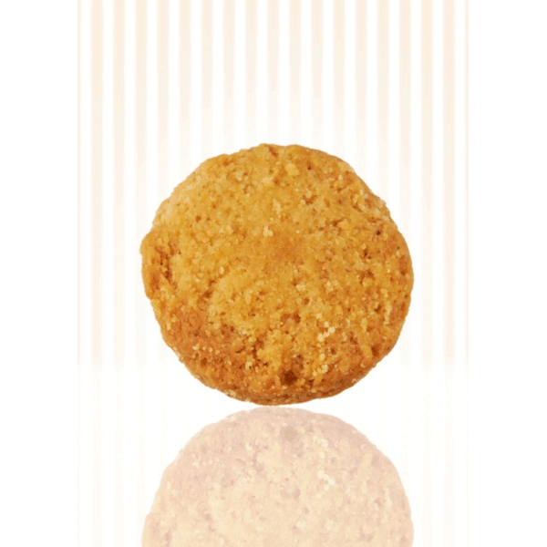 Un sablé doré au maroille, croustillant et rond vu de face, posé sur un fond à rayures verticales beige clair, avec un reflet visible en dessous.