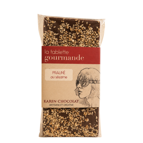 Tablette de chocolat au lait praliné au sésame, parsemée de graines de sésame, emballage transparent Karen Chocolat.