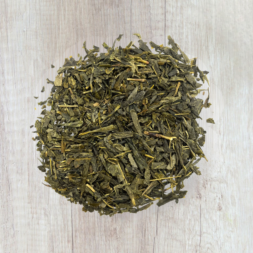 Thé vert Earl Grey bio en vrac, feuilles longues parfumées à la bergamote sur fond en bois clair.