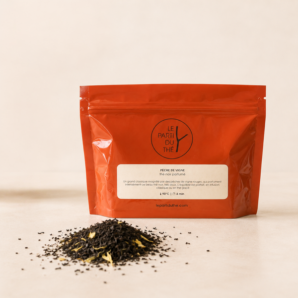 Thé noir parfumé Pêche de Vigne en sachet rouge Le Parti du Thé, avec feuilles de thé en vrac sur fond clair.