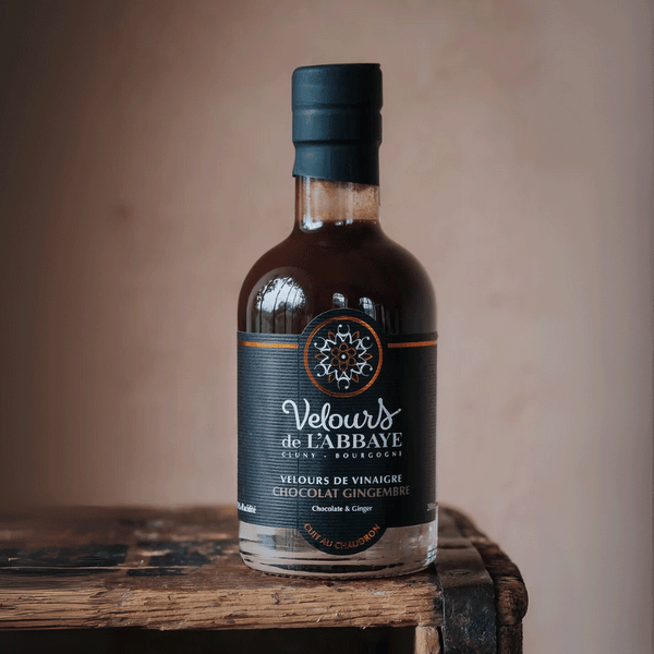 Bouteille de vinaigre chocolat gingembre Velours de l’Abbaye sur caisse en bois rustique.