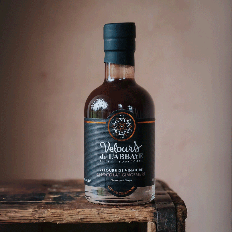 Bouteille de vinaigre chocolat gingembre Velours de l’Abbaye sur caisse en bois rustique.