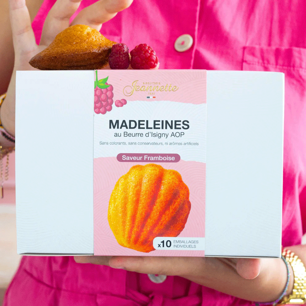 Boîte de madeleines à la framboise tenue dans les mains d'une femme.