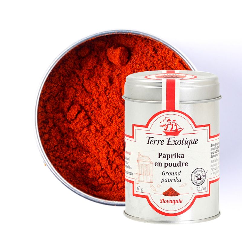 Boîte métallique de Paprika en poudre - Terre Exotique, contenant une fine poudre rouge éclatante, présentée avec son contenu visible en arrière-plan. 